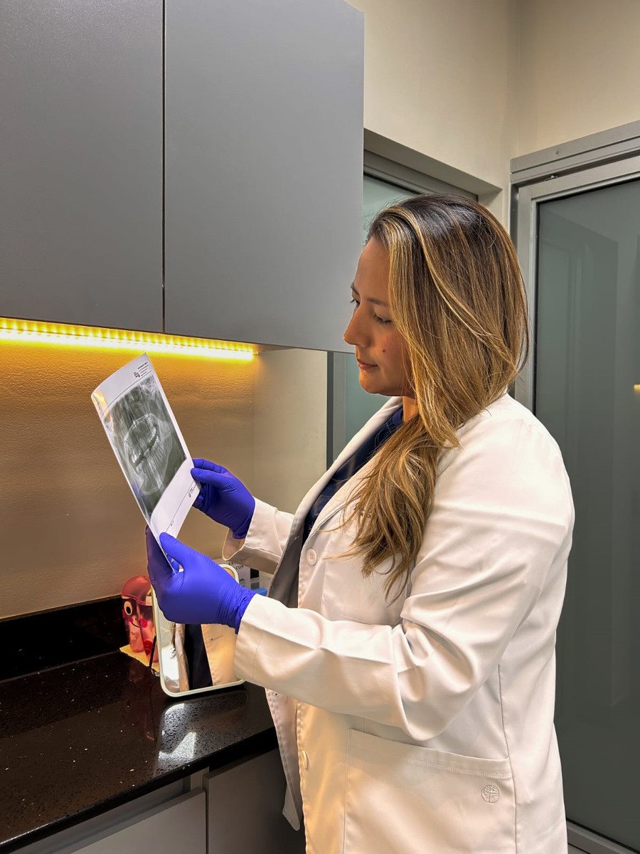 Dra. Kate Quiteño evaluando una radiografía dental en su clínica